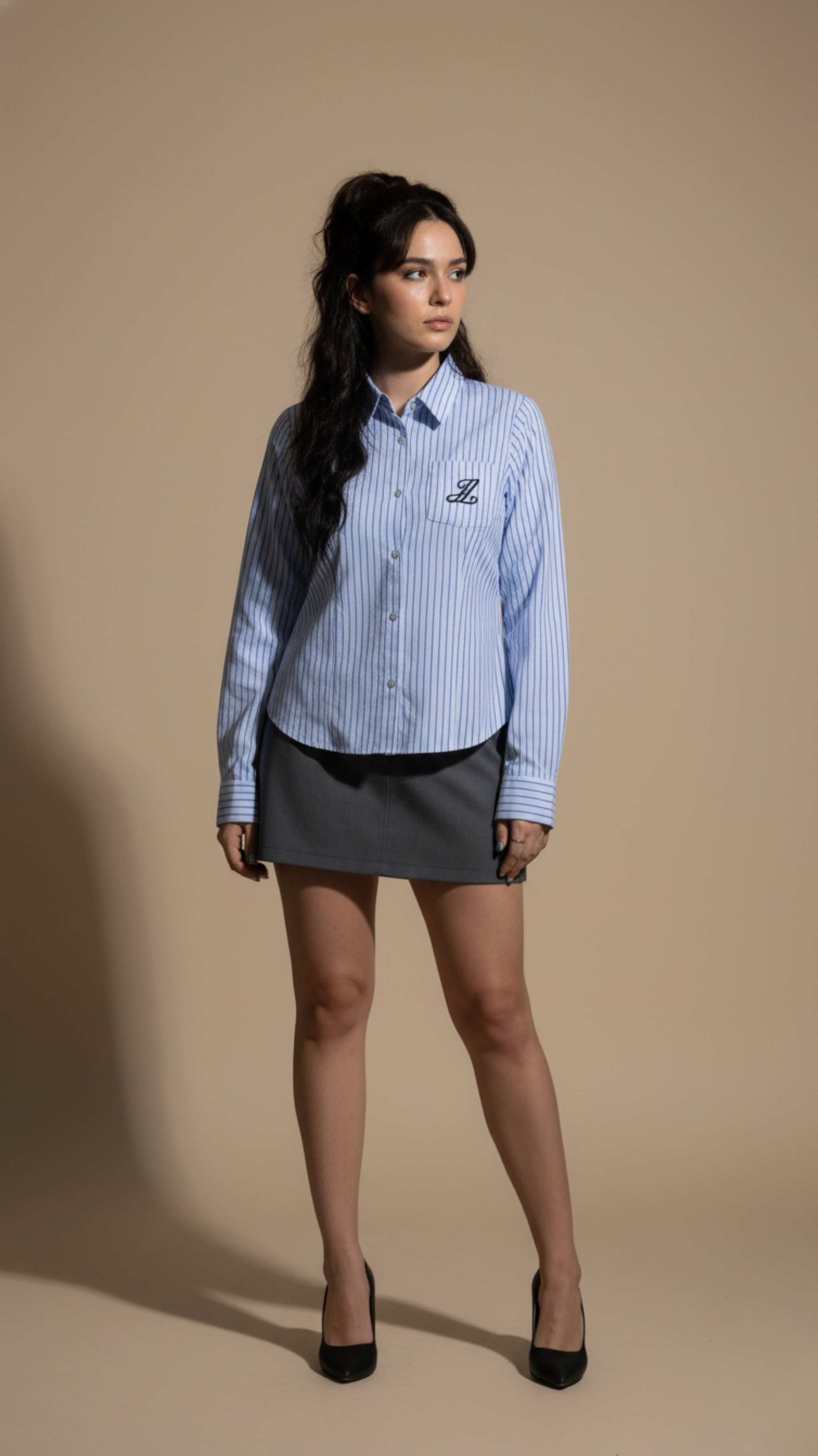 Woman wearing a blue checkered shirt with a logo on a beige background