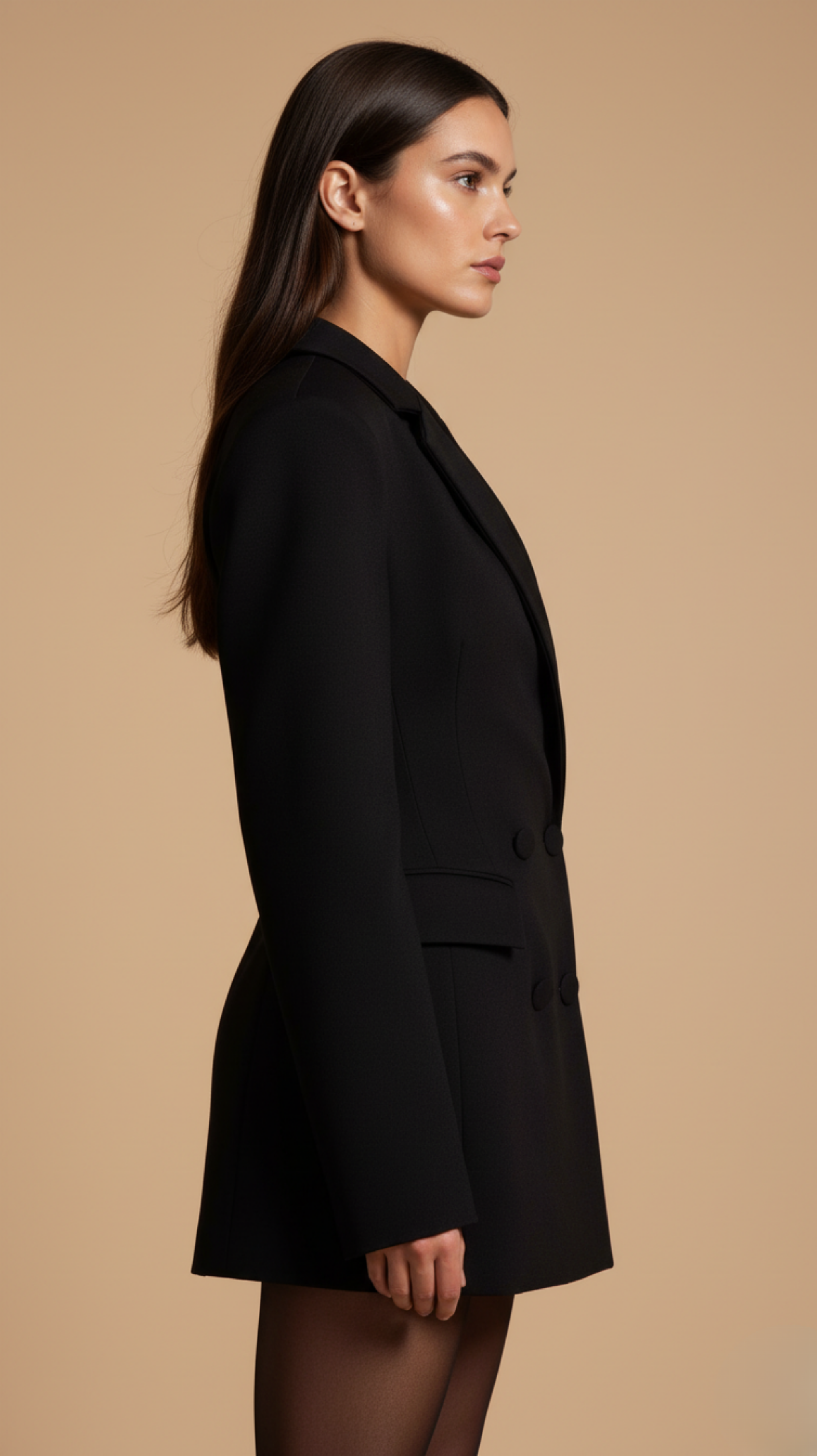 Woman wearing a black coat against a beige background