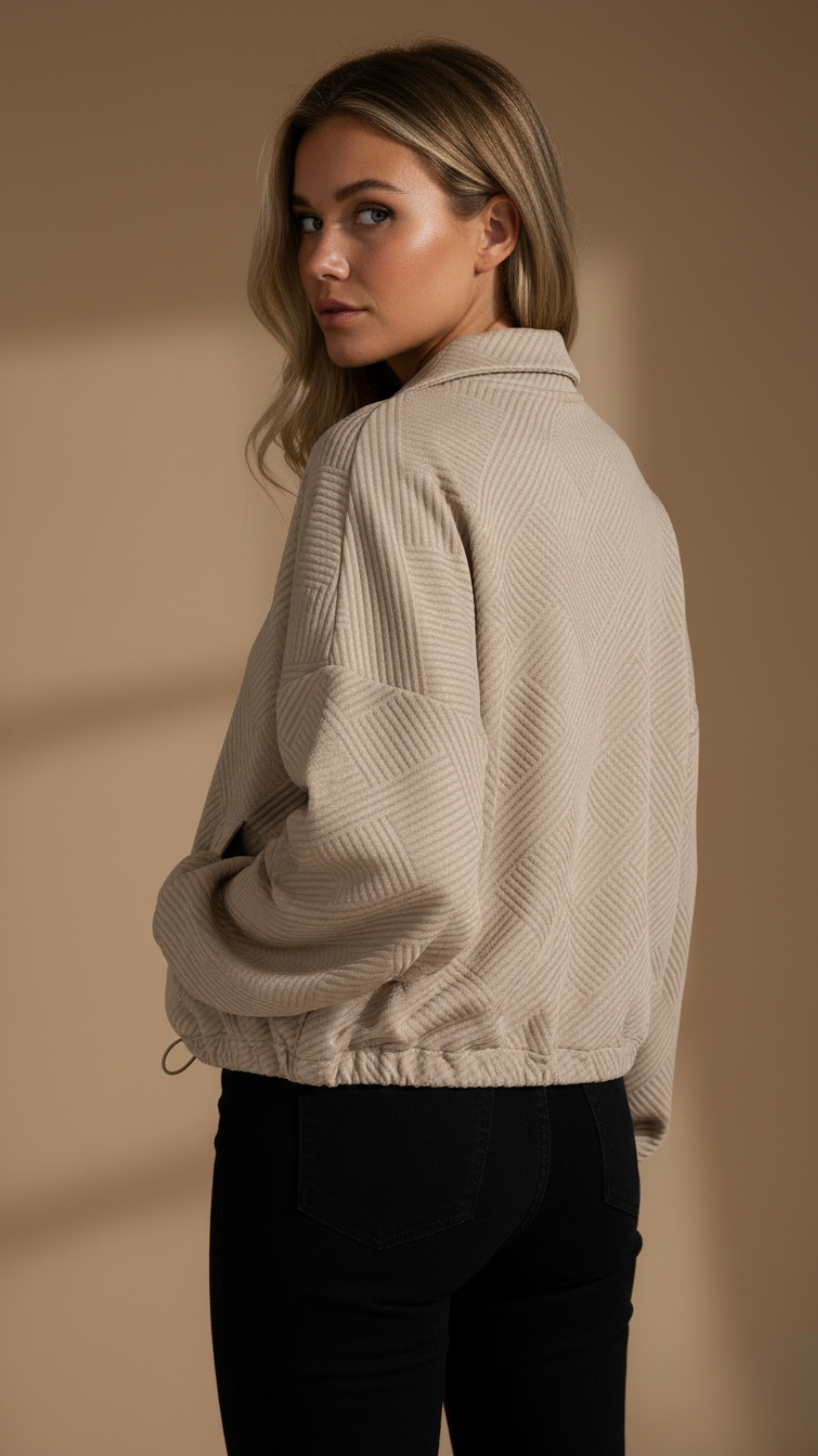 Woman wearing a beige textured sweater against a beige background