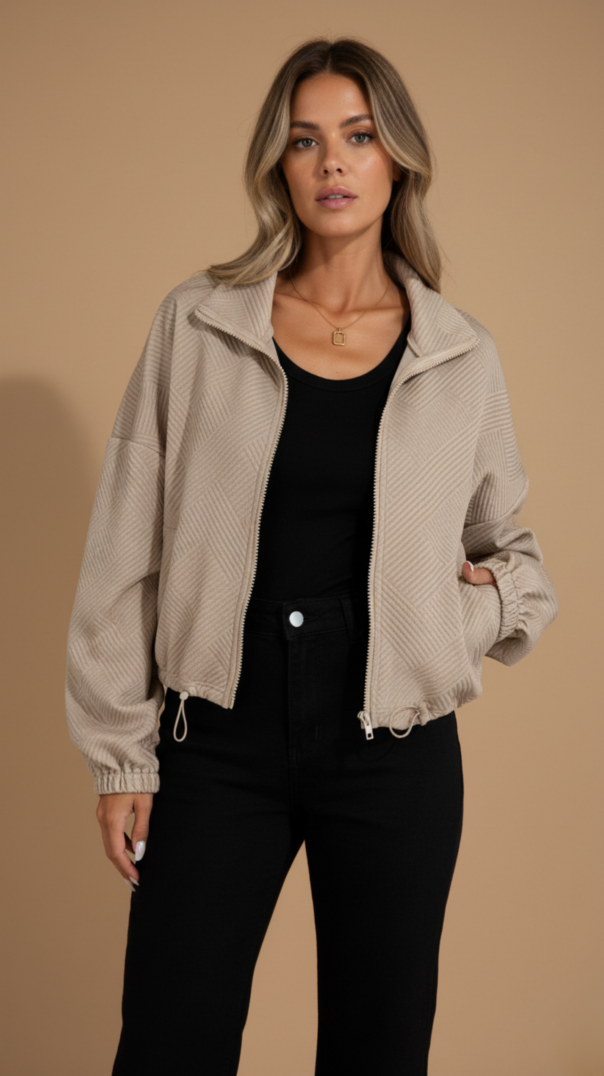 Woman wearing a beige jacket over a black top and pants on a beige background